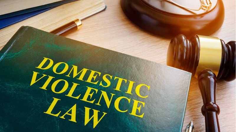 book titled "Domestic Violence Law" next to gavel with domestic violence attorney working at desk