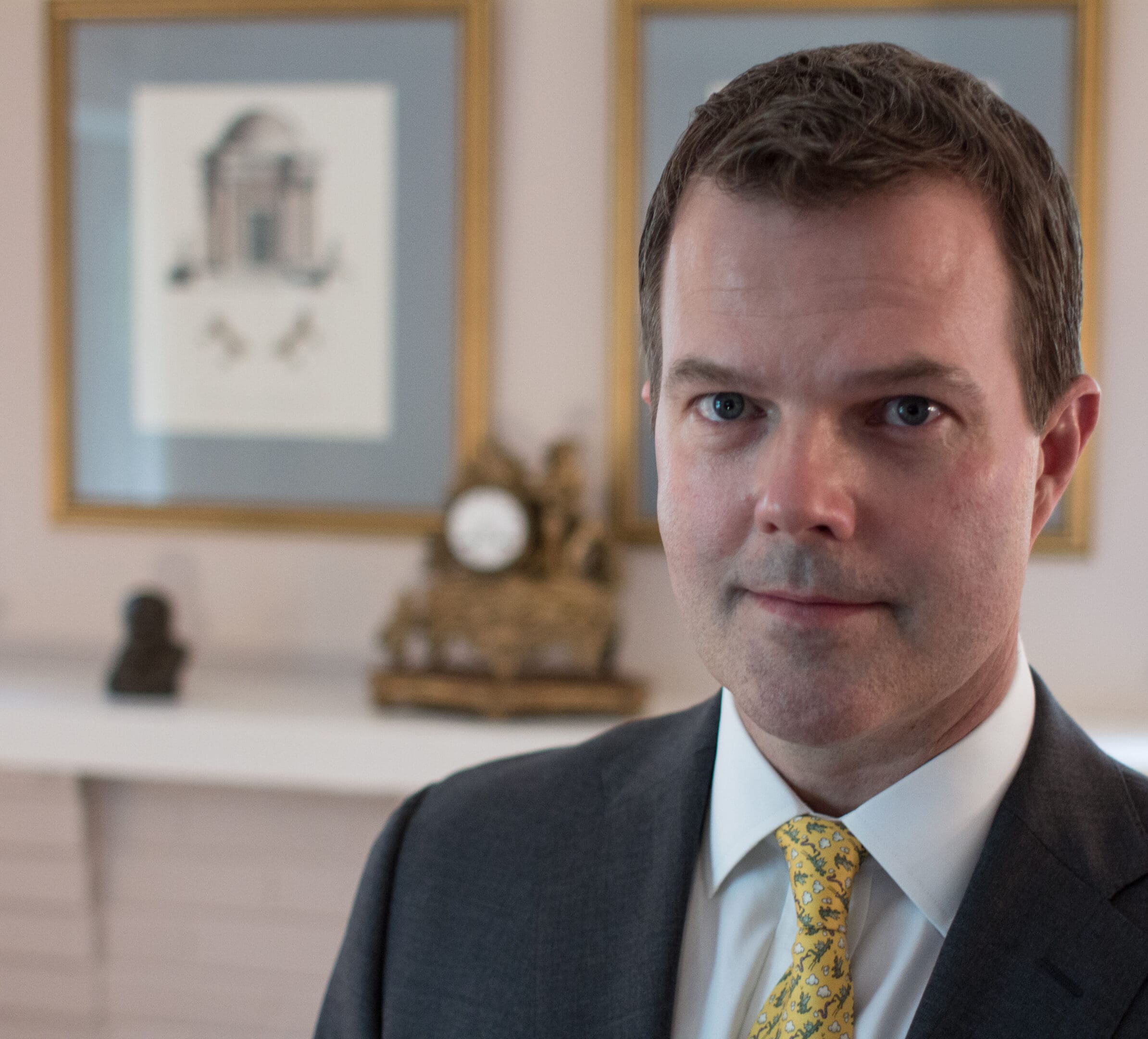 A man in suit and tie standing next to a fireplace.