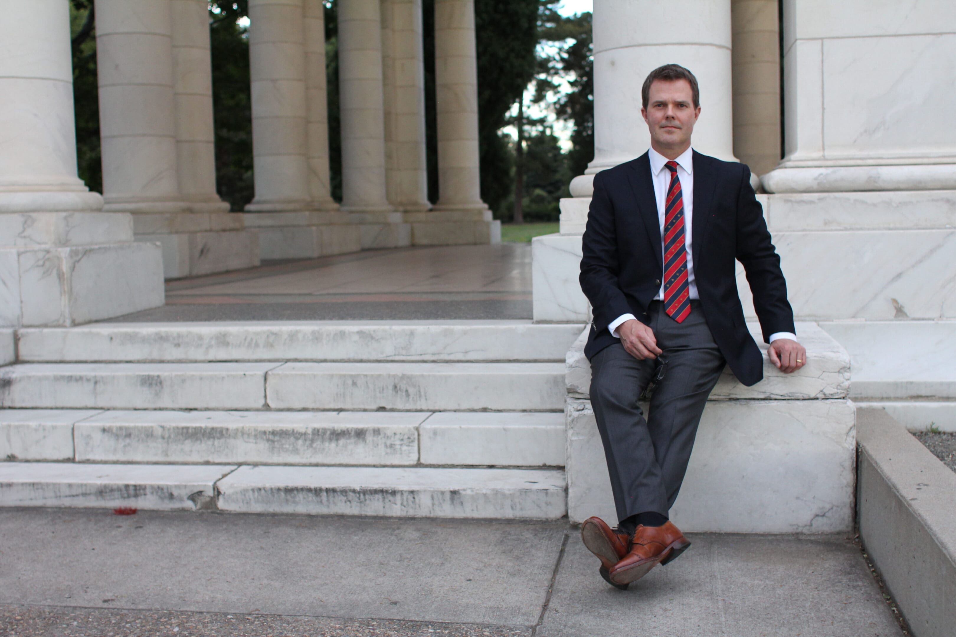 A man in suit and tie sitting on steps.